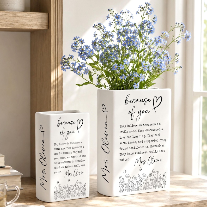 Puede incluir: Dos jarrones rectangulares de cer&aacute;mica blanca con texto impreso en negro que dice because of you, Mrs. Olivia, y un p&aacute;rrafo sobre la bondad y el aprendizaje. Los jarrones est&aacute;n decorados con una ilustraci&oacute;n de flores silvestres.