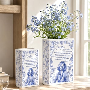 May include: Two rectangular white ceramic vases featuring a blue floral pattern, a portrait of a woman, and the text: Chapter SIXTY-ONE, A HEART THAT'S GROWN WITH Grace, A LIFE THAT'S BLOOMED WITH love, AND A STORY TREASURED BY ALL YOU'VE touched, MAY THIS YEAR REMIND YOU HOW DEEPLY YOU ARE loved, Sophia.