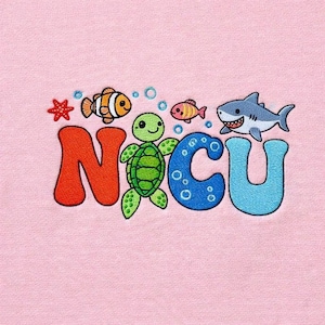 May include: Embroidered design on pink fabric featuring the letters "NICU" in orange and blue, with a green turtle, a shark, and two fish. The design includes bubbles and a starfish.