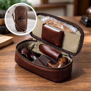 May include: A brown leather pipe case with a zipper, containing a pipe, lighter, and tobacco. The case has a wrist strap and a small pouch with the name "Davit" and a mountain graphic.