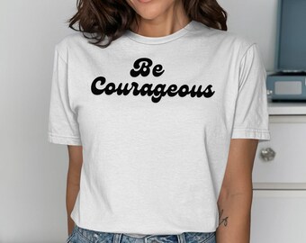 Op de afbeelding: Wit T-shirt met zwarte tekst die "Be Courageous" luidt in een retro-lettertype.
