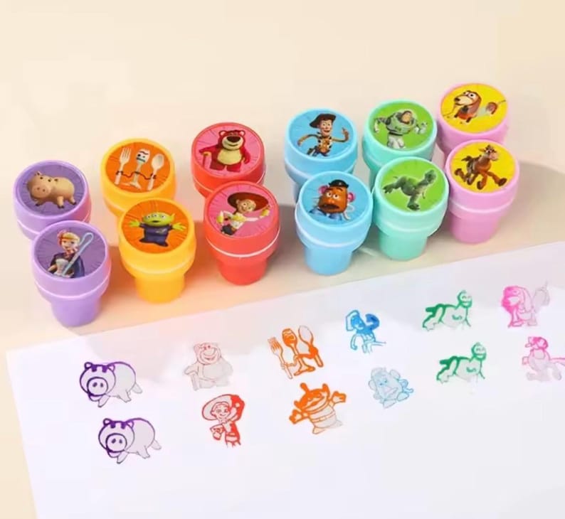 以下が含まれることがあります： 様々なキャラクターが描かれた、カラフルなプラスチック製のスタンプのコレクション。スタンプは紫、黄、赤、青、緑の色合いです。スタンプされた画像が白い面に表示されています。これらのスタンプは、子供向けの工作や教育活動に使用される可能性があります。