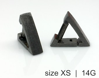 Peut inclure: Deux bijoux corporels triangulaires gris foncé. Le texte "size XS | 14G" est visible en bas de l'image. Les bijoux ont une conception à charnière, avec une base rectangulaire et un sommet triangulaire.