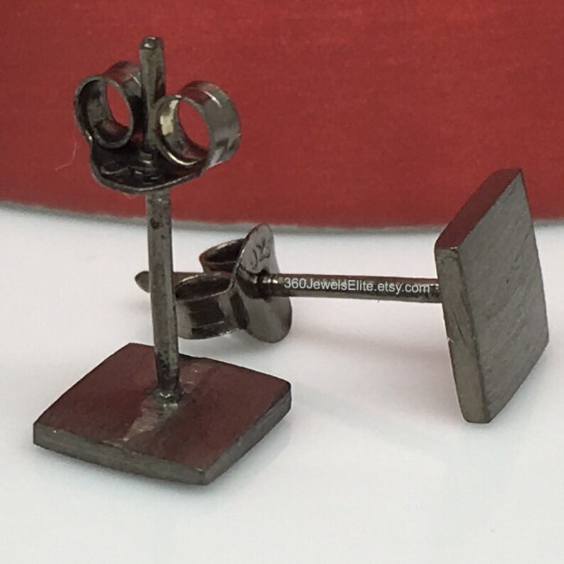 May include: A pair of black square stud earrings with a brushed finish. The earrings have a post and butterfly backing.
