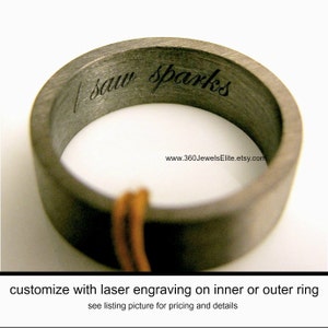 May include: A dark gray ring with the engraved words "I saw sparks" on the inner band. The ring has a matte finish and a simple, modern design. The website address www.360JewelsElite.etsy.com is visible. The ring is a piece of jewelry.