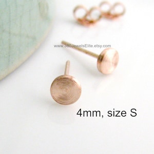May include: A pair of small, round, rose gold stud earrings. The earrings are 4mm in size and are labelled "size S".