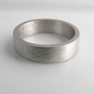 May include: A brushed silver wedding band with a flat, wide profile.