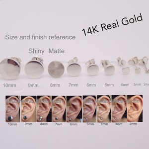 May include: Size and finish reference for 14K real gold earrings.  The earrings are available in shiny or matte finishes and in sizes ranging from 2mm to 10mm.  The image shows the earrings laid out in a row, with the size of each earring labeled below it.