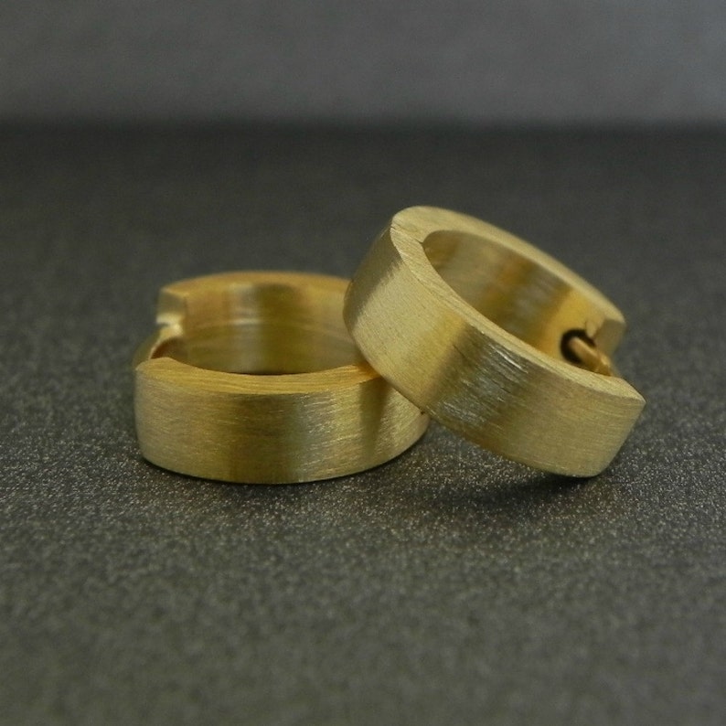 May include: Two gold hoop earrings with a brushed finish. The earrings are simple and elegant.