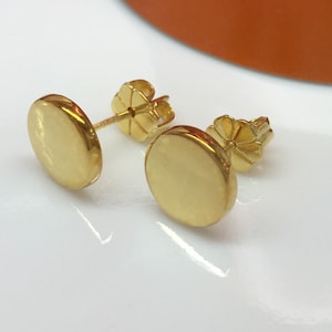 May include: A pair of gold-toned round stud earrings. The earrings are simple and classic, and they would make a great gift for any occasion.