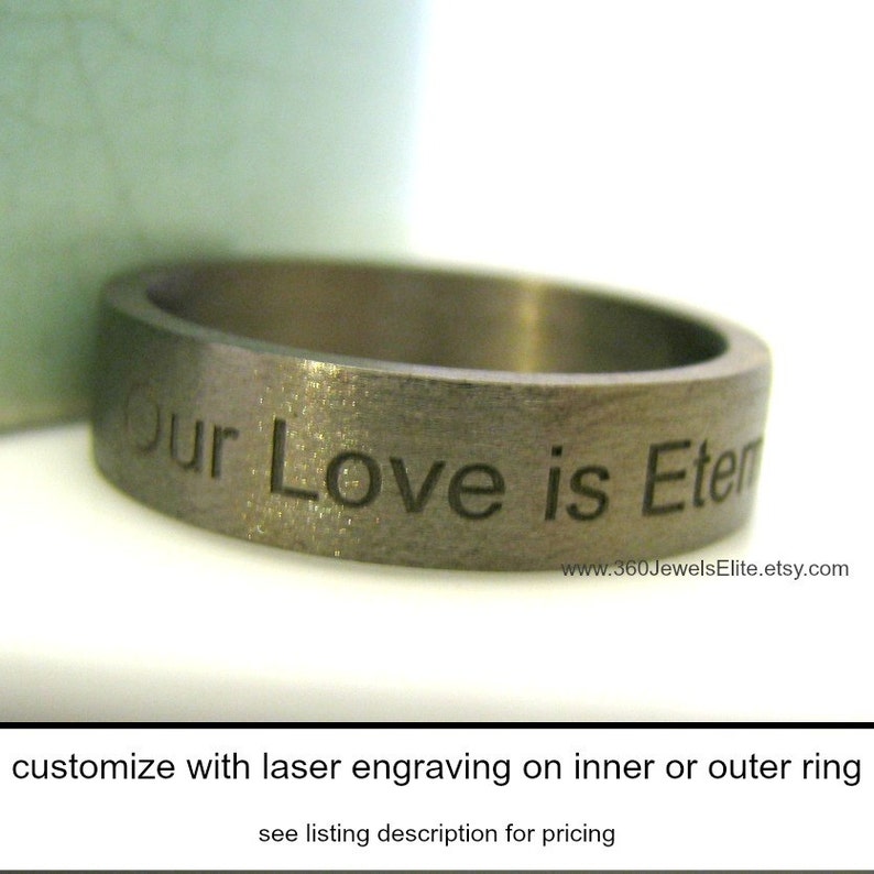 May include: A brushed metal ring with the engraved text "Our Love is Eternal." The ring has a flat, wide band and a matte finish. The Etsy shop URL is visible on the ring. The ring is customizable with laser engraving.