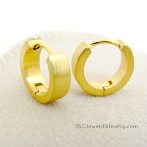 May include: A pair of gold-toned hoop earrings. The earrings are made of brushed metal and have a simple, modern design.