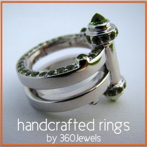 Peut inclure: Une bague en argent avec deux bandes et une pierre précieuse verte sertie dans la bande supérieure. La bague est faite à la main et présente un design unique.