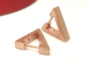 Peut inclure: Une paire de boucles d'oreilles créoles triangulaires en or rose. Les boucles d'oreilles sont en métal brossé et ont un design simple et géométrique.