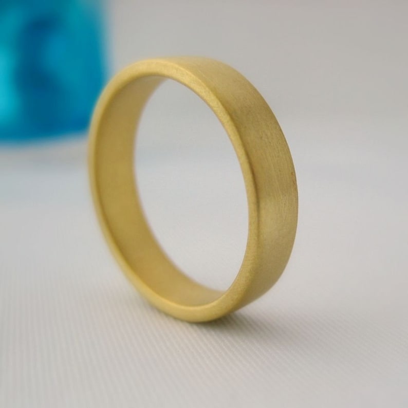 May include: A simple gold wedding band with a brushed finish.
