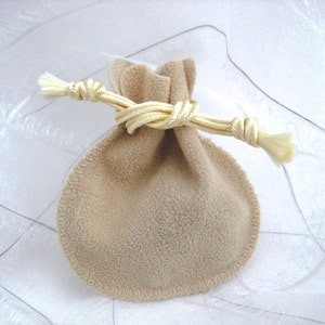 May include: A small, beige drawstring bag made of soft fabric with a cream-colored cord tied in a knot. The bag is perfect for storing small items like jewelry or gifts.