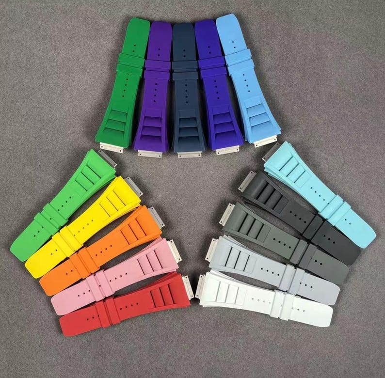 May include: A set of 10 colorful silicone watch bands. The bands are arranged in a semi-circle, with the lighter colors at the top and the darker colors at the bottom. The bands are all the same size and have a smooth, matte finish.