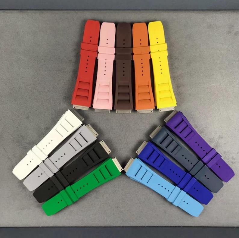 May include: A set of 11 colorful watch bands in various colors, including red, pink, orange, yellow, white, gray, black, green, blue, purple, and dark blue. The bands are made of rubber and have a textured surface.