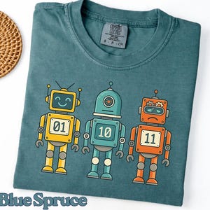 May include: A white ceramic mug with a black handle and the text "But First, Coffee" in a black, bold font. The mug is sitting on a white surface. The mug is approximately 4 inches tall.