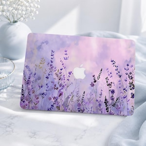 Op de afbeelding: Een laptopskin met een aquarelillustratie van lavendeltakjes in tinten paars en violet tegen een zachte, bewolkte achtergrond. Het ontwerp bevat een centrale uitsparing die het witte Apple-logo zichtbaar laat.