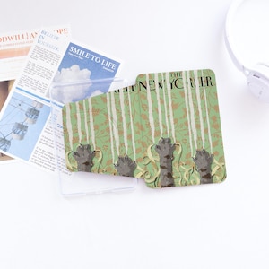 May include: A clear phone case with a green and white patterned insert featuring cat paws and the text "The New Yorker." The case also holds a newspaper clipping and a blue card with the text "Smile to Life."