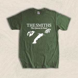 May include: A green t-shirt with a white graphic print of the band The Smiths and the text "The Queen Is Dead".