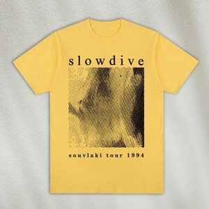 K&ouml;nnte beinhalten: Gelbes T-Shirt mit schwarzem Text, der "slowdive" lautet, und einem schwarz-wei&szlig;en Grafikbild. Der Text unter dem Bild lautet "souvlaki tour 1994".