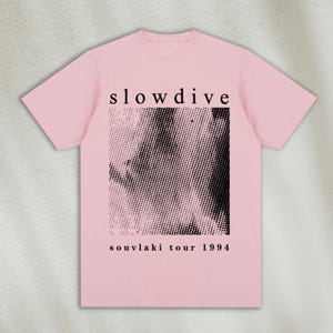 K&ouml;nnte beinhalten: Rosa T-Shirt mit einem schwarz-wei&szlig;en Grafikdruck eines Gesichts und dem Text "slowdive souvlaki tour 1994"