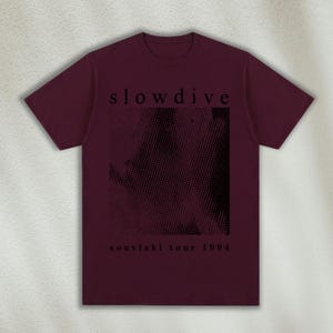K&ouml;nnte beinhalten: Ein maroonfarbenes T-Shirt mit einem schwarzen grafischen Druck eines strukturierten Musters und dem Text "slowdive souvlaki tour 1994".