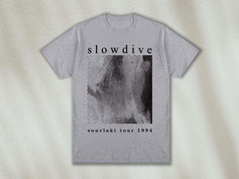 K&ouml;nnte beinhalten: Graues T-Shirt mit schwarzem Text, der "slowdive" und "souvlaki tour 1994" lautet. Das Shirt zeigt ein Schwarzwei&szlig;-Halbtonbild.