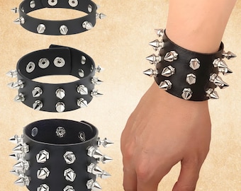May include: Black leather wristbands with silver spikes. The image shows three wristbands, one worn on a wrist. The wristbands have adjustable closures with multiple snap settings. The spikes are evenly spaced around the bands.
