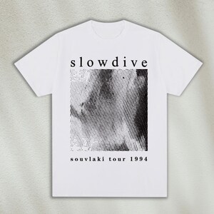 K&ouml;nnte beinhalten: Wei&szlig;es T-Shirt mit einem schwarz-wei&szlig;en Grafikdruck eines Gesichts mit dem Text "slowdive souvlaki tour 1994" unter dem Druck.