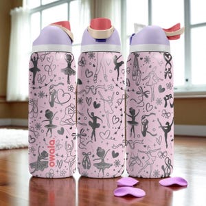 Pode incluir: Três garrafas de água de aço inoxidável com base rosa claro e um padrão repetitivo de bailarinas, sapatilhas de ballet, laços e corações em cinza escuro. Cada garrafa tem uma tampa lavanda com fecho coral e o logótipo da marca Owala.