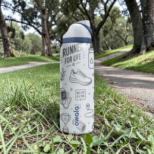 May include: A white and blue Owala water bottle with the text "RUNNER FOR LIFE" and running-themed illustrations. The bottle is standing on a grassy surface with a path and trees in the background.