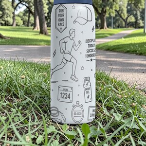 May include: A white water bottle with a navy blue lid, featuring a running theme. The bottle has illustrations of a runner, a hat, and text that reads "Run Your Own Race" and "Discipline Today Success Tomorrow."
