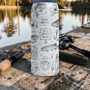 May include: A white and navy blue water bottle with fishing-themed illustrations and text. The bottle features drawings of fish, fishing gear, and the phrases "Fish More Worry Less" and "Life is Better at the Lake."