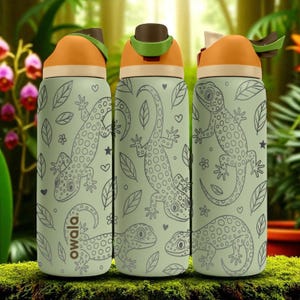 May include: Three light green water bottles featuring a repeating line art pattern of spotted lizards, leaves, and small hearts. Each bottle has an orange and brown lid with a green accent piece. The word Owala is printed vertically on the left bottle.