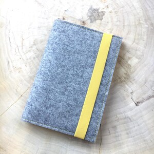 May include: A gray felt notebook cover with a yellow elastic band closure.
