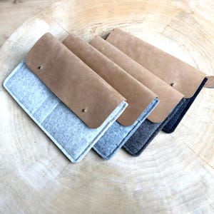 May include: Four leather and felt laptop sleeves in different colors. The sleeves are stacked on top of each other, with the brown leather sleeve on top. The sleeves are made of a soft, durable material and are perfect for protecting your laptop from scratches and bumps.