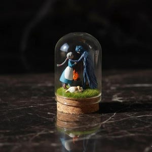 Puede incluir: Un terrario en miniatura con forma de c&uacute;pula de cristal que presenta figuras de dos personajes de una pel&iacute;cula de fantas&iacute;a. La escena incluye un peque&ntilde;o fuego, un perro durmiendo y hierba verde. La c&uacute;pula est&aacute; sobre una base de corcho.