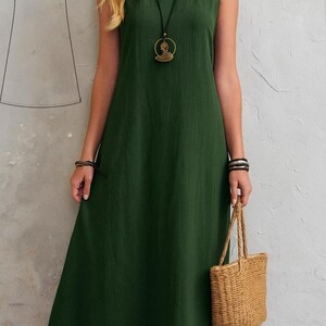 May include: A sleeveless, dark green dress with a round neckline and a flowing A-line skirt. The dress is paired with a woven tote bag and a long necklace. A dress pattern is in the upper left corner.