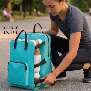 May include: A teal roller skate backpack with black straps and a top handle. The backpack has a front pocket and is designed to carry roller skates. The roller skates are secured on the side of the backpack. The image shows the backpack being opened.