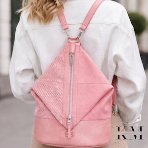 May include: A pink backpack with a unique geometric design. The bag features a woven texture on the top flap and a smooth, solid pink material on the main body. It has a silver zipper and adjustable straps.