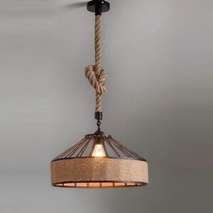 May include: A black metal pendant light with a rope cord and a woven jute shade. The light is hanging from a ceiling.