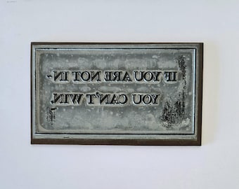 May include: A metal sign with a motivational quote: "If you are not in, you can't win."