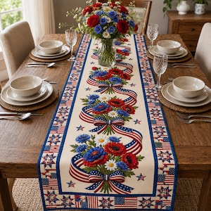 May include: A patriotic table runner with a cream-colored background, featuring red, white, and blue floral bouquets and American flag ribbon designs. The runner is bordered with stars and stripes, perfect for a festive dining table setting.