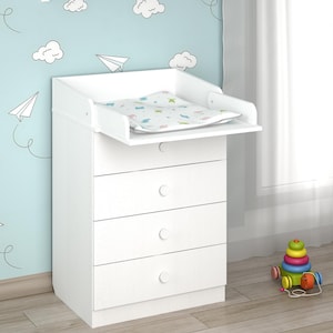 Könnte beinhalten: Weiße Wickelkommode mit drei Schubladen und einer Wickelauflage. Der Wickeltisch hat einen erhöhten Rand auf der Wickelfläche. Der Raum hat eine hellblaue Wand mit Wolken- und Papierflugzeug-Aufklebern.