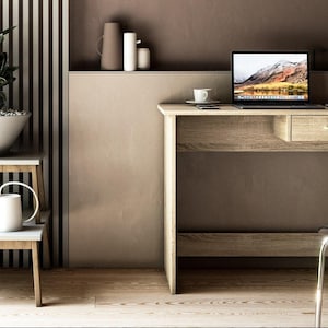 Può includere: Una scrivania in legno chiaro con un cassetto, un laptop e una tazza e un piattino. Un tavolino laterale contiene una pianta in una ciotola bianca e un annaffiatoio. Lo sfondo presenta un muro a strisce e oggetti decorativi.