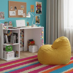 Peut inclure: Un bureau blanc avec des étagères intégrées, un ordinateur portable et une lampe de bureau. Un pouf jaune est posé sur un tapis rayé coloré. Un skateboard est appuyé contre le bureau, et des guirlandes lumineuses ajoutent une touche festive.