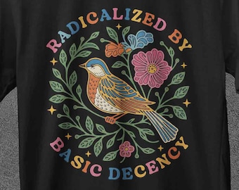 May include: Black t-shirt with a colorful graphic of a bird, flowers, and the text "RADICALIZED BY BASIC DECENCY" in a circular design. The brand name "JoJoTeez" is at the top.